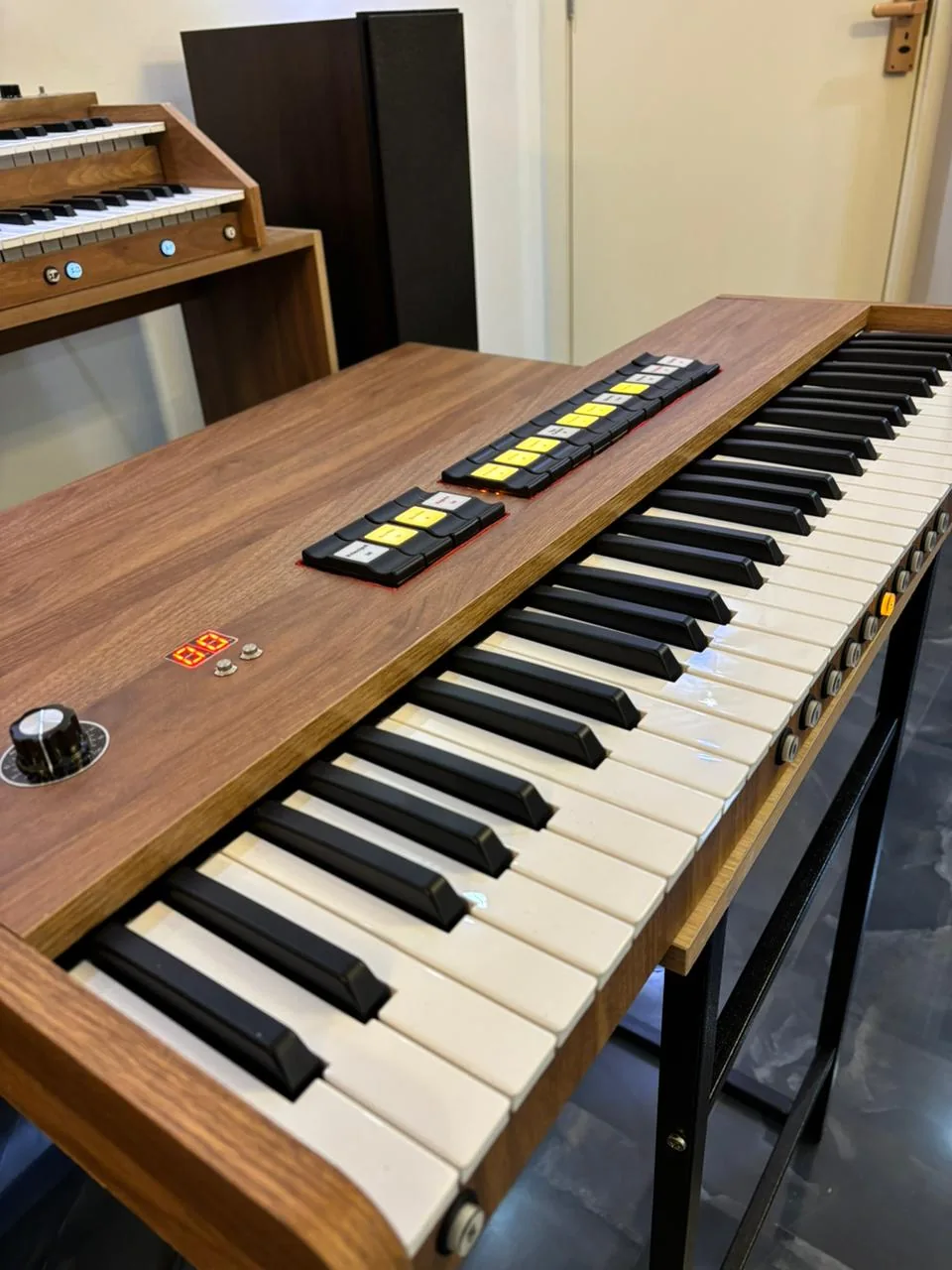 Órgão digital compacto, com teclado e painel de registros no móvel de madeira.